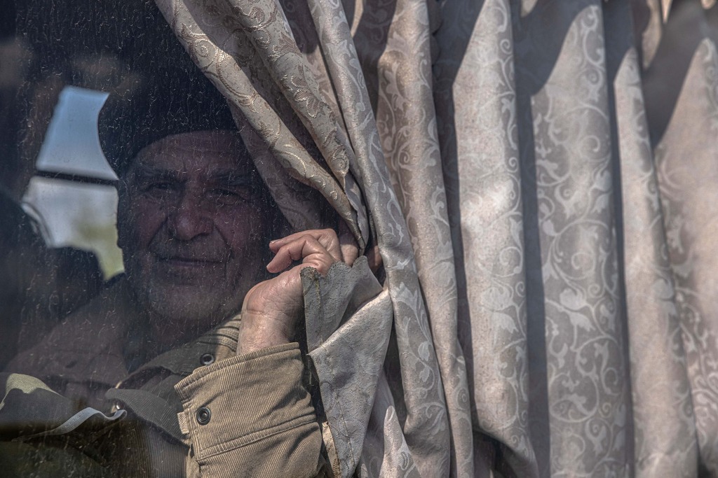 An elderly man looks on as he sits in a bus after arriving from the frontline town of Orikhiv, at the evacuation point in Zaporizhzhia, Ukraine