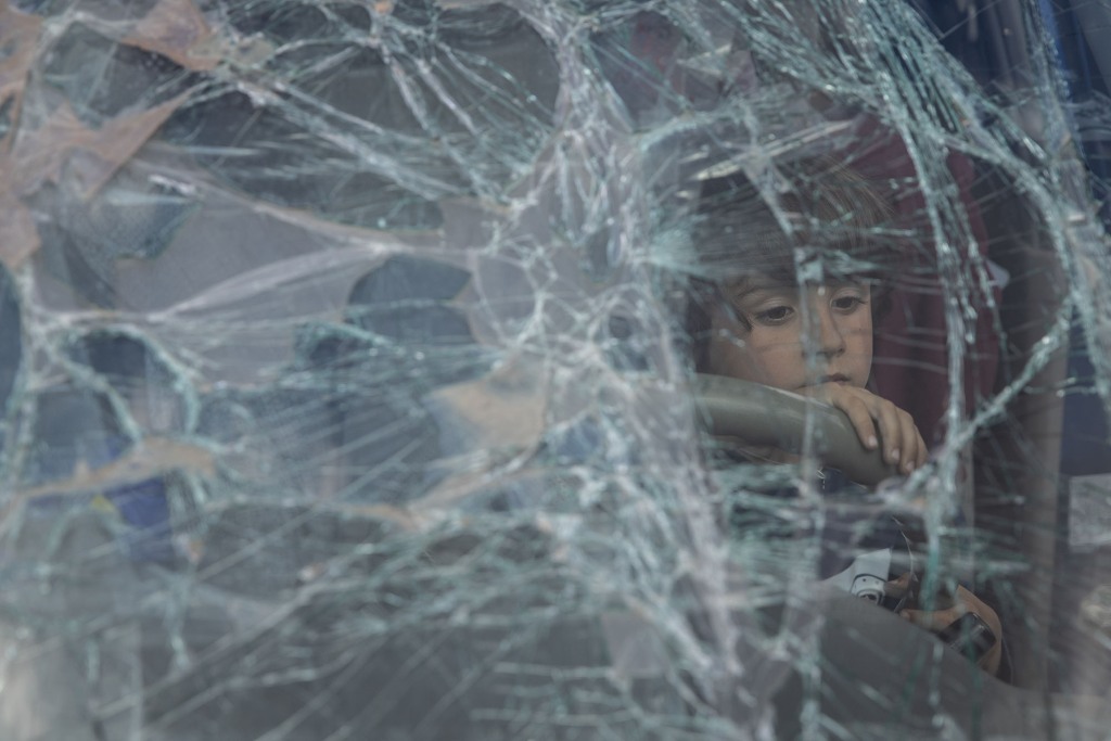 A boy from Mariupol looks out through the smashed windscreen of his family's car